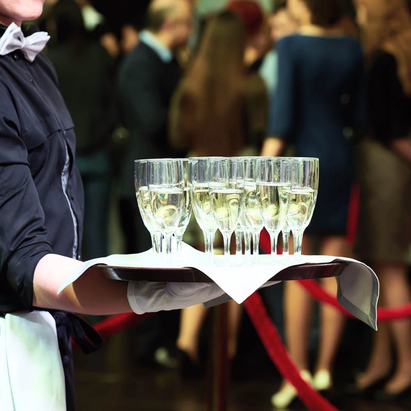 catering or celebration concept. Waiter holding a tray with glasses of vine at party